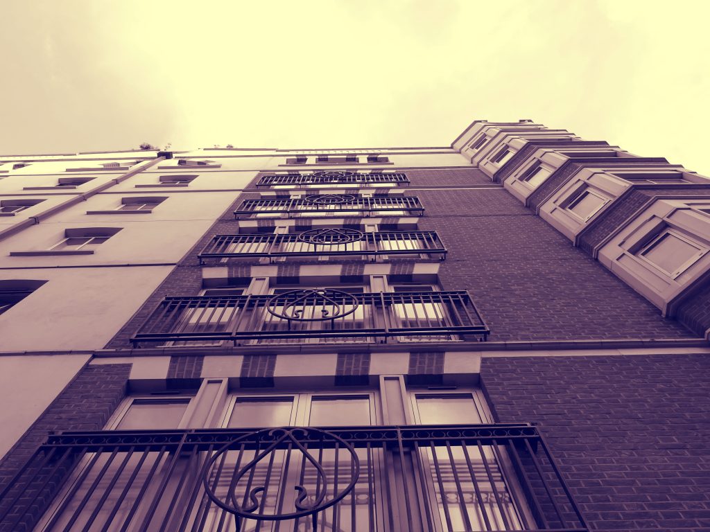 A sepia-toned low angle shot highlighting the design of a modern apartment building facade.